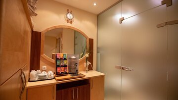 A bright room with a modern sink and a mirror. Tea bags and cups are ready on a table.