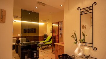 An elegant reception area with modern furniture and soft lighting. On the left side, there is a large mirror and a relaxing atmosphere.