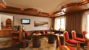 A cozy interior with modern seating and warm wood design. Large windows provide plenty of natural light and a welcoming atmosphere.