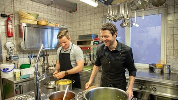 Two men are preparing food together in a modern kitchen. They appear cheerful and focused.