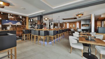 A modern restaurant with a stylish bar and comfortable seating areas. The atmosphere is cozy and welcoming.