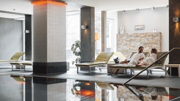 A relaxing wellness area with loungers and a calm ambiance. A couple in bathrobes enjoys the atmosphere.