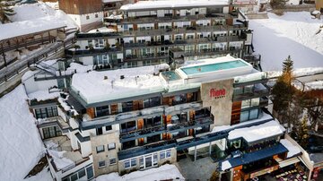 A modern hotel in the snow with a rooftop pool. The surroundings are wintry and picturesque.