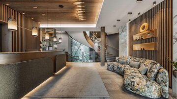 A modern reception area featuring a long counter and an inviting seating corner. The walls are adorned with wooden paneling and decorative elements.