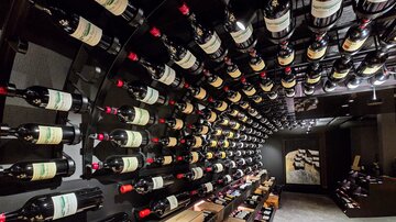 A wine cellar with many bottles of red wine hanging on a round wall. The atmosphere is elegant and inviting.