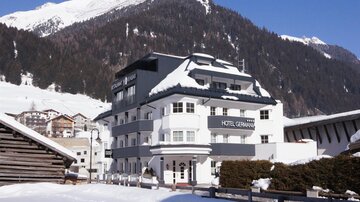 A charming hotel in the snow, surrounded by mountains. The clear winter landscape conveys an inviting atmosphere.