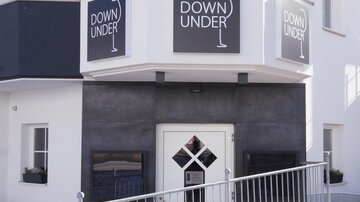 A modern building with an entrance area. Above the door is the sign "DOWN UNDER".