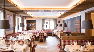 An elegant restaurant with wooden decor and stylish seating. The tables are carefully set, and it radiates a cozy atmosphere.
