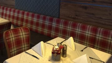 A cozy restaurant with red checked benches and elegantly set tables. A stylish lamp hangs over one of the tables.