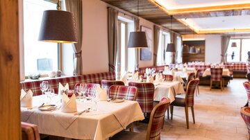 A stylish restaurant with set tables and modern lamps. The decor is cozy and inviting.