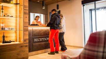 A reception area with a friendly reception team. Two guests are at the reception desk to check in.
