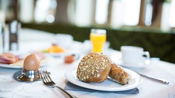 A delicate breakfast with a bun, an egg, and fresh fruit. Served with a glass of orange juice.