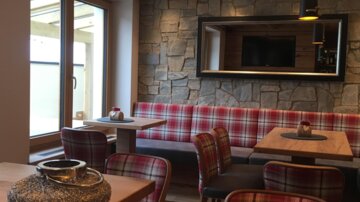 A cozy interior with wood and stone accents. The seating is upholstered in checked fabric, creating an inviting atmosphere.