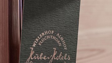 A door sign made of green material hangs on a door. It displays the inscription "Hotel" and some information about the stay.