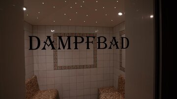 A steam bath with tiled walls and benches. Ceiling lights create a pleasant atmosphere.