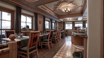 An inviting restaurant with wooden decor and cozy tables. The windows let in plenty of light and create a pleasant atmosphere.