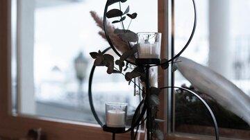 A stylish decoration with candles and plants in a modern holder. The composition is placed on a windowsill and offers an elegant look.