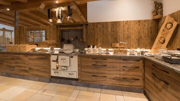 A warm and welcoming wooden kitchen with rustic charm. Several cooking utensils and dishes are on the countertop.