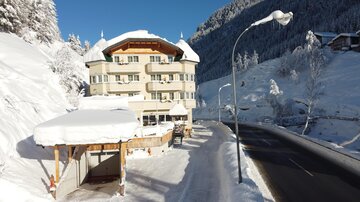 A charming hotel in the snow with a well-snow-covered roof. The surroundings are wintry and picturesque with a quiet street.