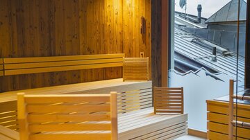 A bright sauna area with wooden benches and large windows. The room offers a relaxing view of the outdoor landscape.