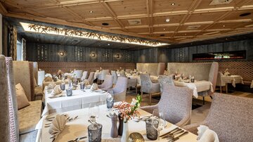 An elegant restaurant with stylishly set tables. The decor consists of soft colors and cozy seating.