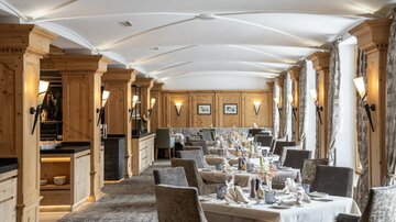 An elegant restaurant with wooden elements and a cozy atmosphere. The tables are beautifully set and create an inviting ambiance.