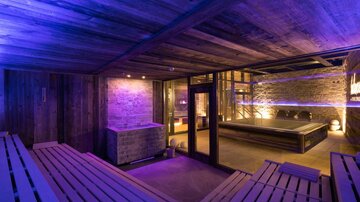 A luxurious wellness area with wooden paneling and soft lighting. The sauna is stylishly furnished and invites relaxation.