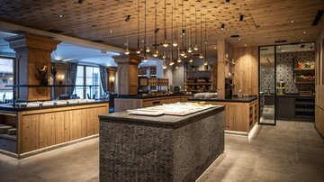 A modern restaurant with wooden and stone accents. The lighting creates a warm atmosphere.