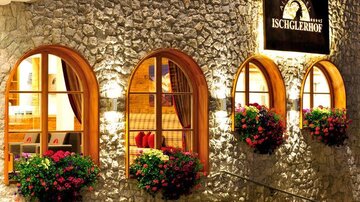 An inviting hotel with a natural stone facade and large windows. Colorful flower boxes adorn the entrance and provide a cozy atmosphere.