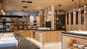 Modern kitchen with wooden elements and elegant lighting. The space is open and inviting, ideal for a relaxed dining experience.