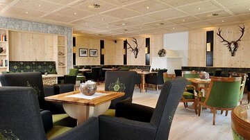A modern restaurant with wooden elements and cozy seating. The walls are decorated with artistic details and pictures.
