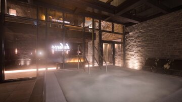 A relaxing wellness area with a hot tub and soft lighting. The walls are made of stone, creating a cozy atmosphere.