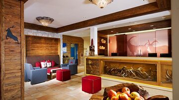 An inviting reception area with wooden paneling and comfortable seating. In the foreground is a bowl of fresh apples.