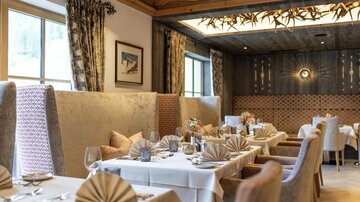 An elegant restaurant with cozy seating areas and beautifully set tables. The atmosphere is warm and inviting, ideal for a fine meal.