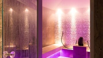 An elegant spa area with soft purple lighting and a modern design. The atmosphere feels relaxing and inviting.