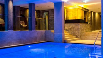 An elegant swimming pool with blue water and modern design elements. The space is stylishly lit and offers a relaxing atmosphere.