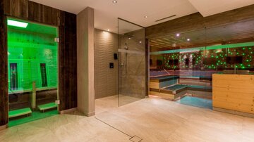 A modern wellness area with a relaxing atmosphere. There is a pool and a sauna with gentle green light accents.