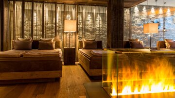 A stylish living room with wooden furniture and soft lighting. The modern fireplace adds a cozy atmosphere.