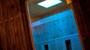 A modern infrared sauna with gentle lighting. The inscription "INFRAROT" is clearly visible.