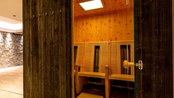 A modern sauna area with rows of wooden chairs and warm lighting. The atmosphere feels relaxing and inviting.