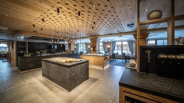 An elegant restaurant with wooden details and modern furniture. The open kitchen and appealing decor create an inviting atmosphere.