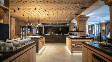 An elegant restaurant with wood paneling and a modern bar. The lighting creates a warm and inviting atmosphere.