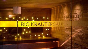 A relaxing room with warm light that serves as a bio herbal sauna. The walls are made of stone, and an ethereal ambiance invites relaxation.