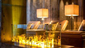 A modern living room with a glass fireplace and warm light. Pleasant atmosphere with elegant furniture and soft lighting.