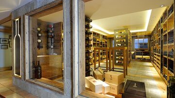 An elegant wine cellar with wooden shelves and various wine bottles. Soft lighting creates an inviting atmosphere.