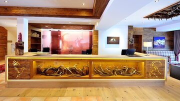 A modern hotel reception with an artistically designed wooden reception desk. In the background, cozy seating areas and decorations are visible.