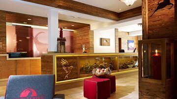 A modern reception with warm wooden tones and stylish decorations. In the foreground are comfortable seating furniture and a decorative table.