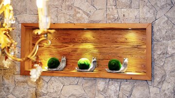A wooden-paneled wall with three decorative snail figures and illuminated green balls. In the background, stones are visible, giving the scene a rustic touch.