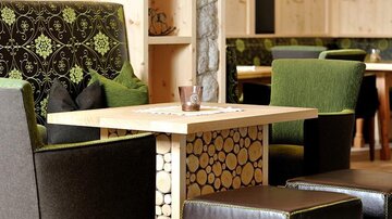 A cozy seating area with stylish chairs and a wooden table. The modern furniture is in shades of green and brown, creating an inviting atmosphere.
