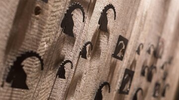 A wooden surface with several black silhouettes representing a head with antlers. The figure is arranged in various sizes and distances.